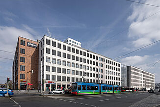 Blick auf das Stadtquartier Seetor City Campus in Nürnberg mit einer Straßenbahn vor dem Gebäude.